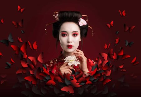 An photo of a geisha girl holding a white flower surrounded by a swirl of red and black butterflies